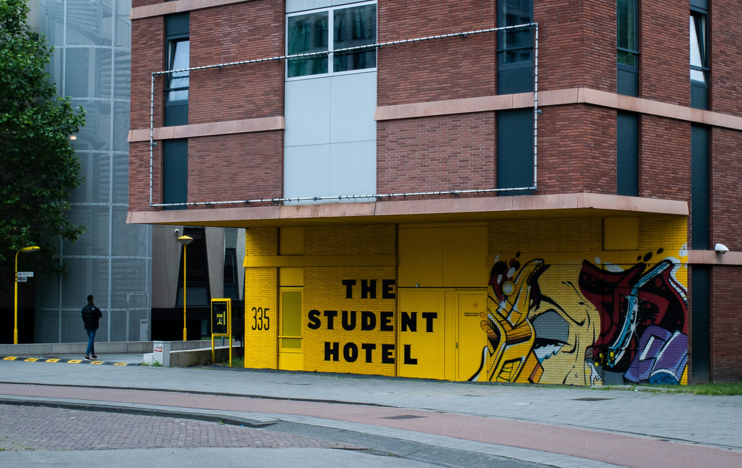Modern brick building with vibrant graffiti art and street view in city setting.