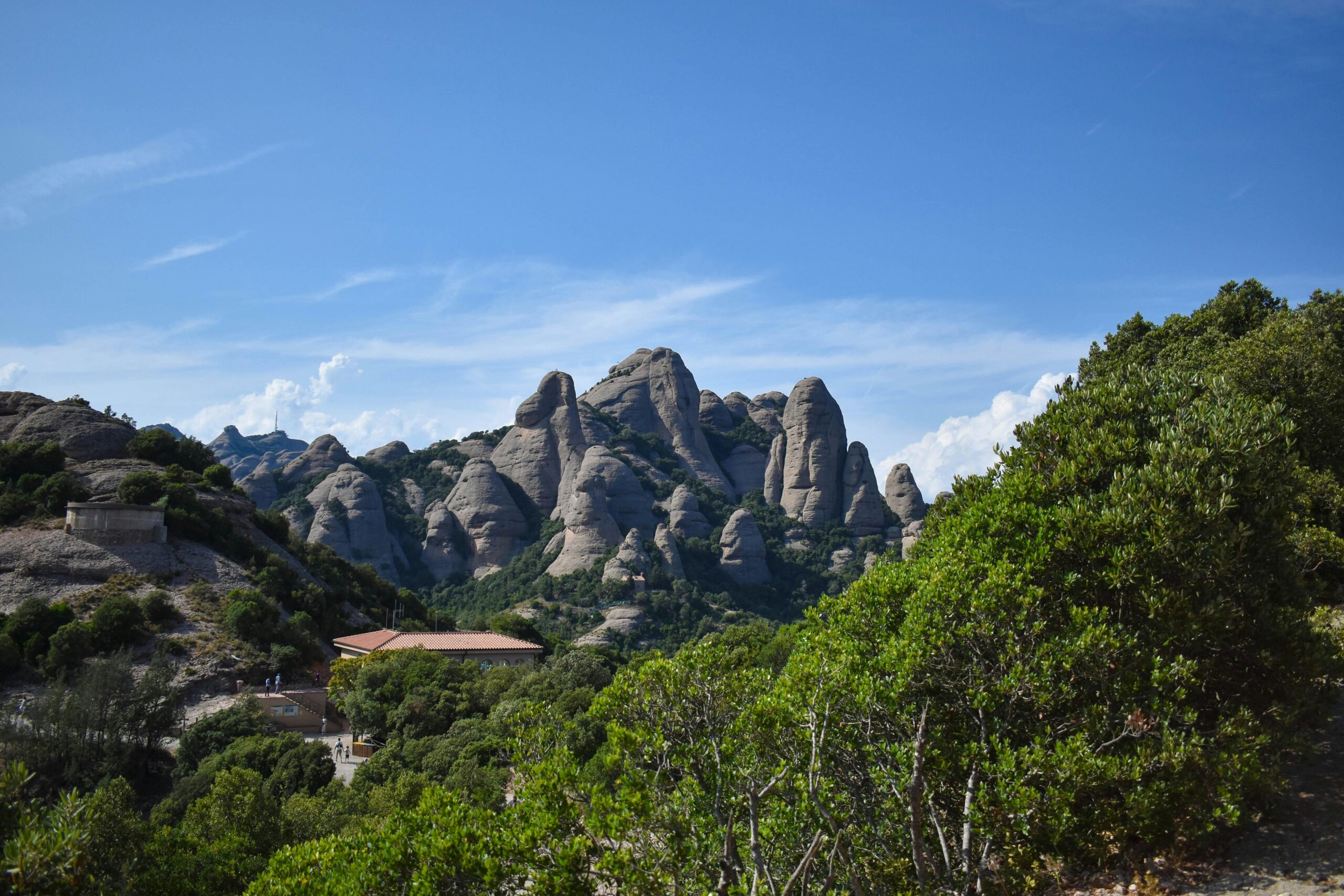 Stunning view of Montserrat mountains with lush greenery under clear blue skies in Spain.