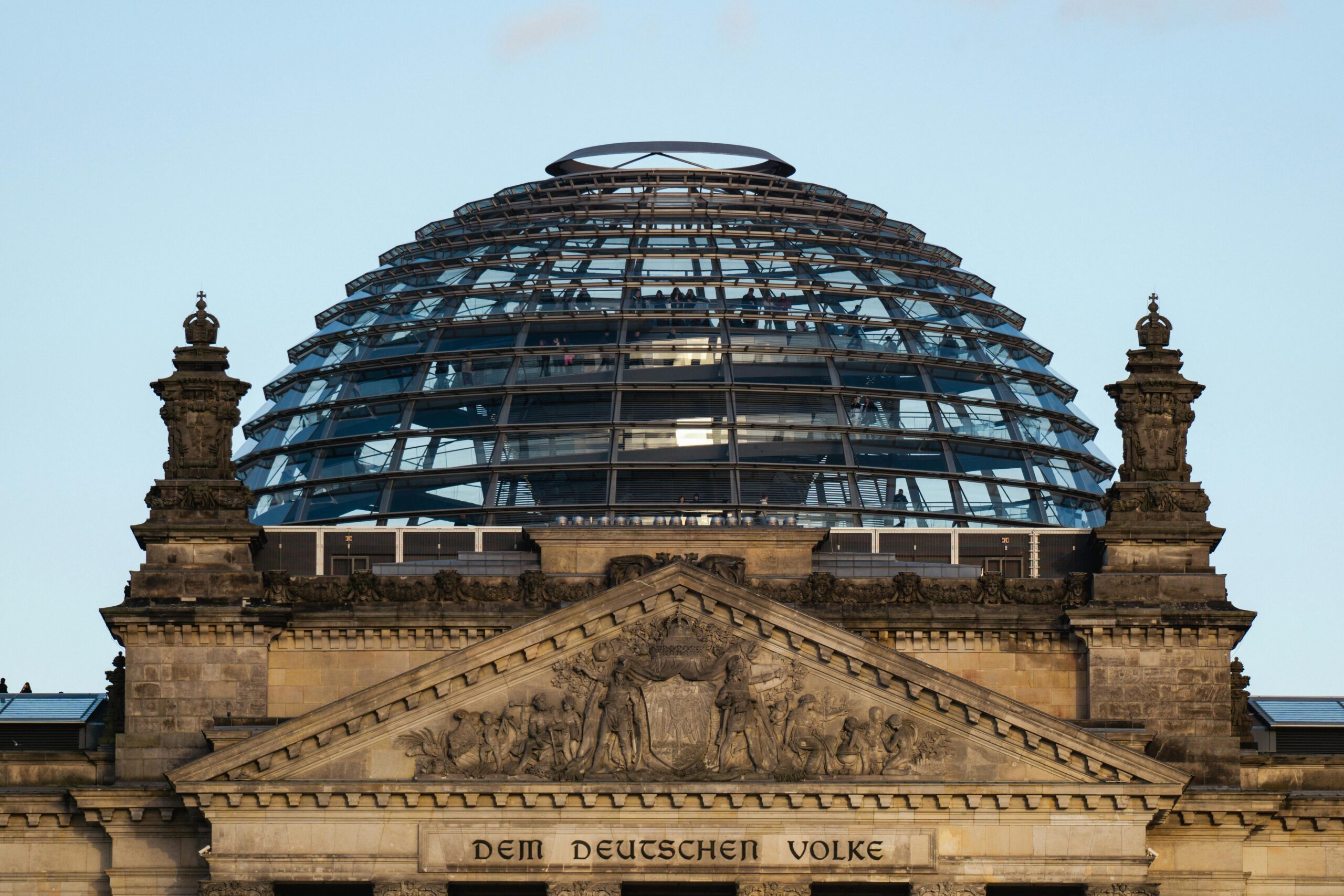 The iconic glass dome of the Reichstag in Berlin, Germany, against a clear sky.