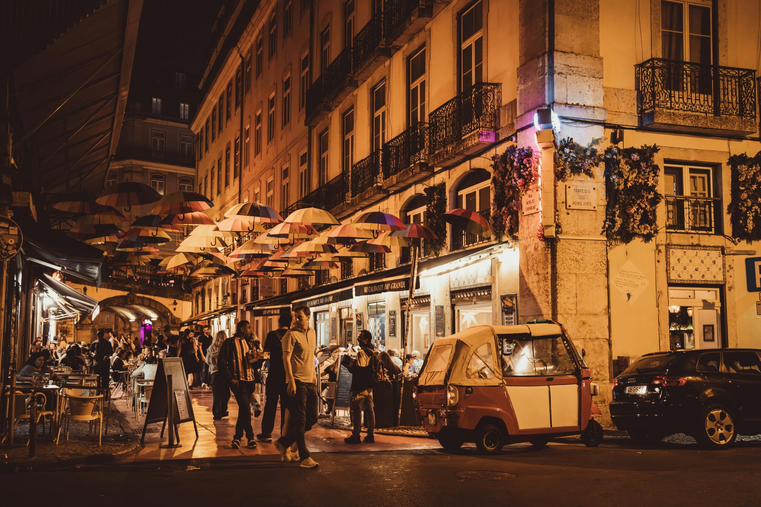 Charming street scene with umbrellas and cafes in Lisbon at night.