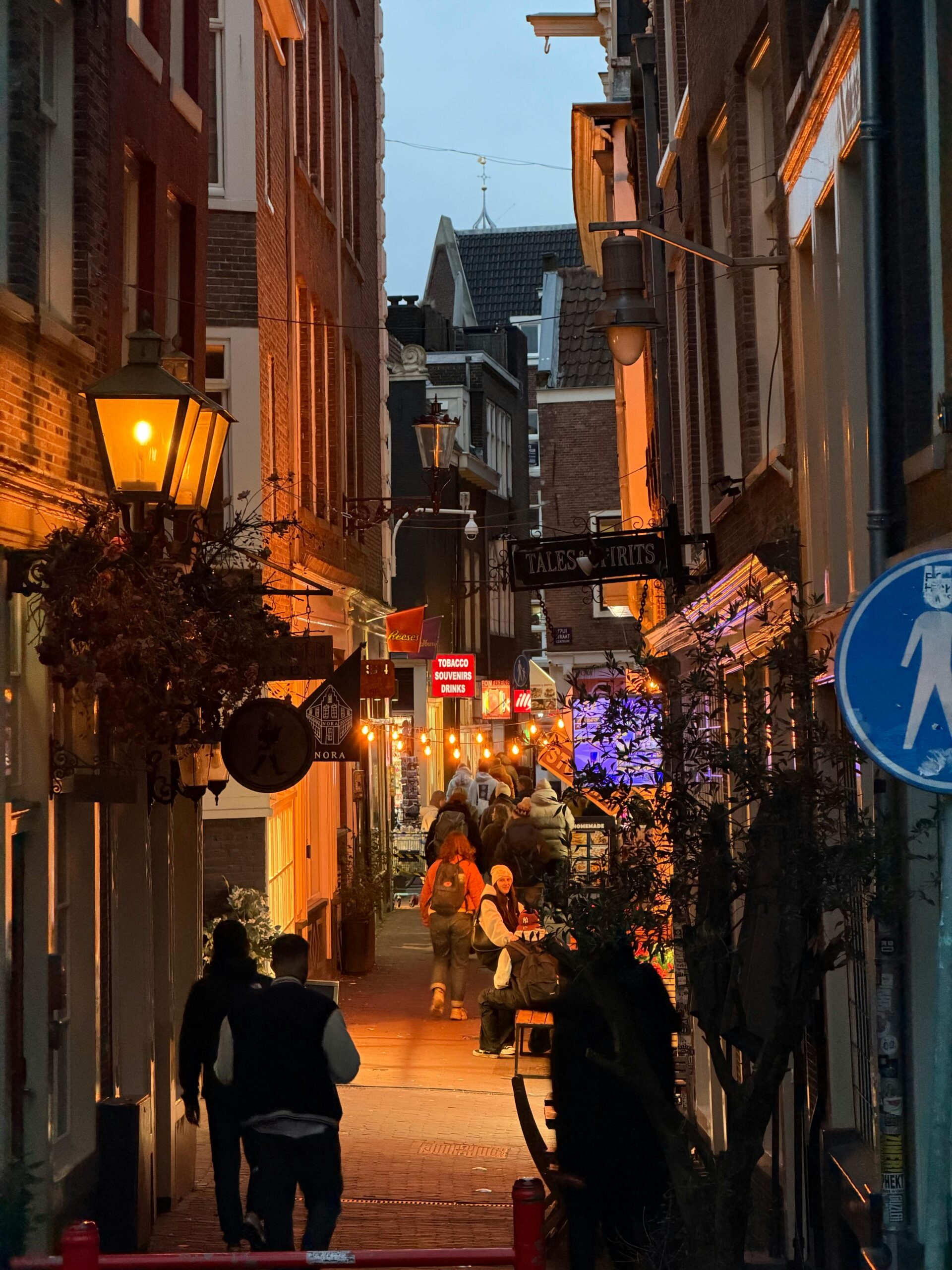 Charming Amsterdam street scene with warm lighting and bustling atmosphere during twilight.