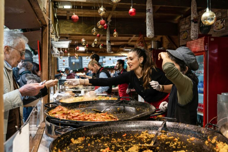 Vibrant market scene with people enjoying paella during the holiday season.