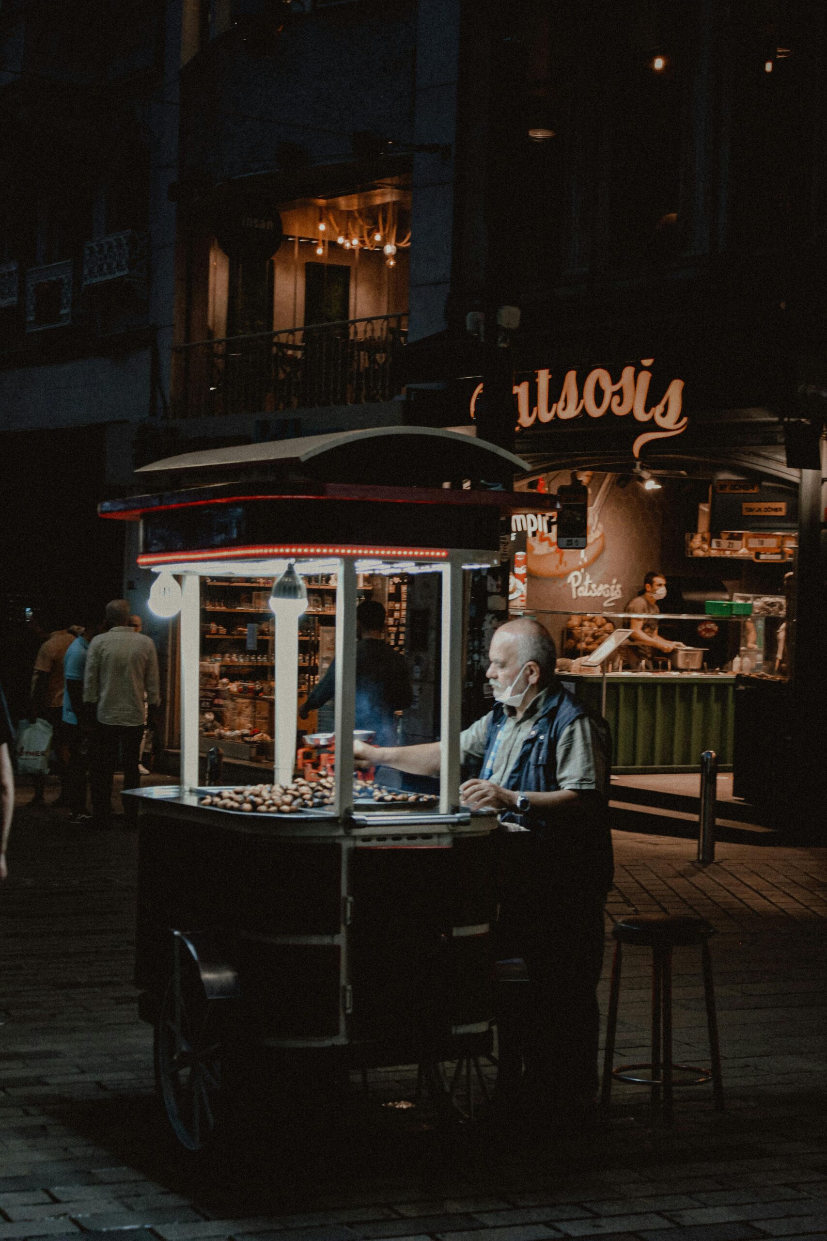 A food cart vendor serving customers in an urban street setting at night, exuding a traditional ambiance.