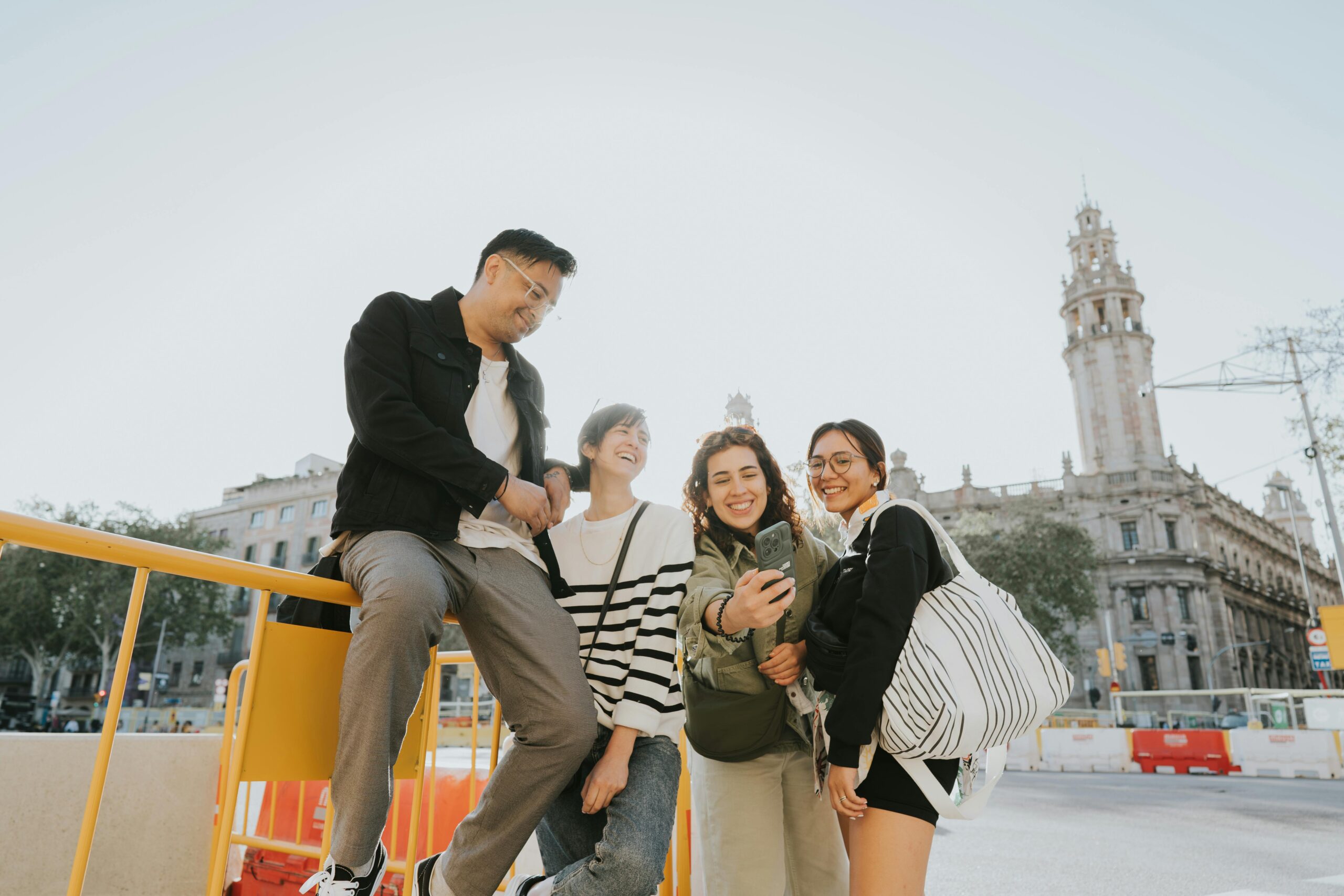 Happy group of friends taking a selfie outdoors near historic buildings in Barcelona, Spain.